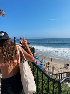 a woman taking a photo on her cell phone at the beach