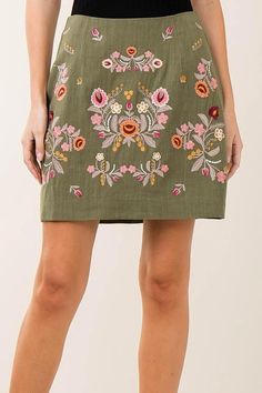 a woman is wearing a skirt with flowers on the front and side, while she has her hands in her pockets