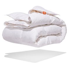 three white pillows stacked on top of each other in front of a white background with an orange tag