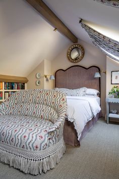 a bedroom with a bed, couch and bookshelf in the corner next to it