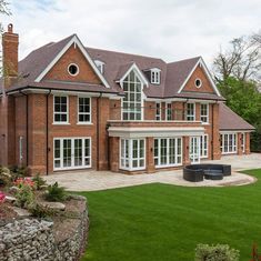 a large red brick house sitting on top of a lush green field