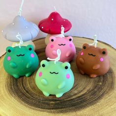 four small ceramic animals sitting on top of a wooden table next to each other and one has a candle in the shape of a frog