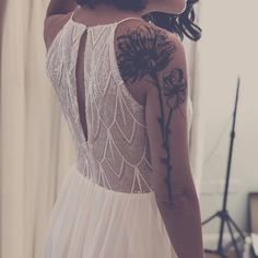 a woman in a white dress with tattoos on her back