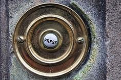 a round metal object with the word press on it's center hole, in front of a stone wall