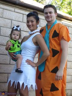 a man and woman in costumes standing next to a little boy with a baby on his lap