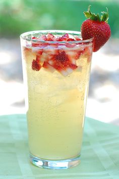 a glass filled with ice and strawberries on top of a table