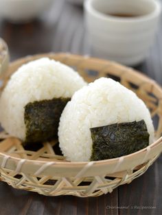 two pieces of sushi sitting in a basket on a table next to a cup