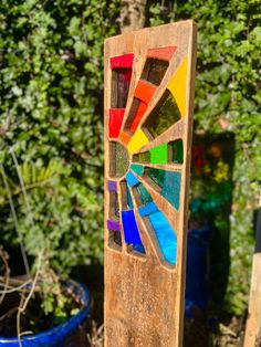 a wooden stand with stained glass on it in front of some bushes and trees,