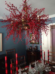 a chandelier hanging from the ceiling in a dining room with red candles on it