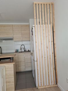 a kitchen with white walls and wooden slats on the wall, next to a refrigerator freezer