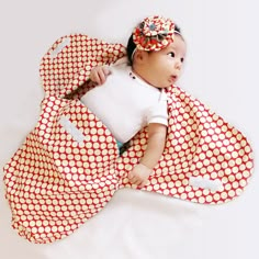 a baby laying on top of a red and white blanket