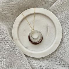 a white plate with some jewelry on it and a gold necklace hanging from the middle