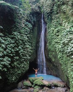 a man standing in front of a waterfall with his arms up and hands raised above the water