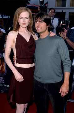 a man and woman standing next to each other on a red carpet at an event