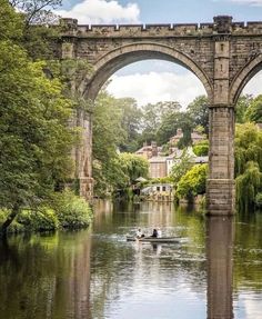 two people in a small boat under an old bridge