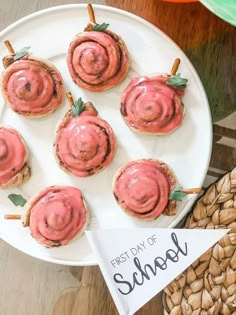 small sandwiches with pink icing on them are sitting on a plate next to some nuts