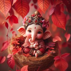 a small statue of an elephant sitting in a nest with red leaves surrounding it on a tree branch