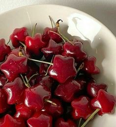 a white bowl filled with cherries on top of a table