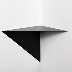 a black shelf mounted to the side of a white wall