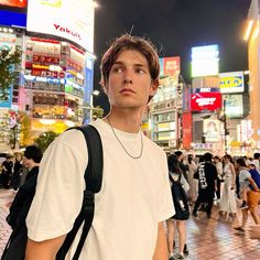 a man standing in the middle of a busy city street at night with lots of people