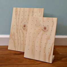 two wooden peg boards with holes in them on the floor next to a blue wall