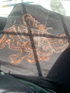 a black shirt with an orange dragon drawn on it