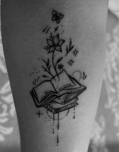 a black and white photo of a book with flowers coming out of it on the thigh