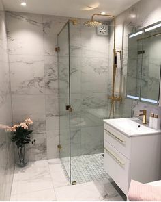 a bathroom with marble walls and flooring, white sink, shower stall and mirror