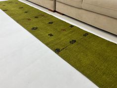 a green rug sitting on top of a white floor next to a couch and chair