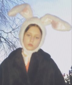 a woman wearing a bunny ears costume standing in front of a tree