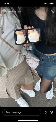 a woman taking a selfie with her cell phone while sitting on the ground next to another person