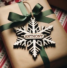 a present wrapped in brown paper with a green ribbon and snowflake ornament