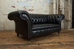 a black leather couch sitting on top of a wooden floor