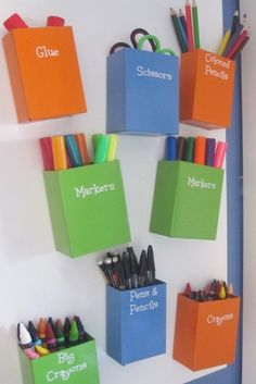 there are many pencils and markers in the boxes on the wall next to each other