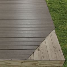 a close up of a wooden deck with grass in the background