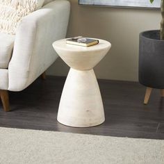 a small table with a book on it next to a chair and potted plant