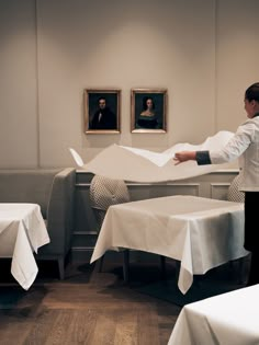 a man is throwing papers into the air in front of two tables with white tablecloths