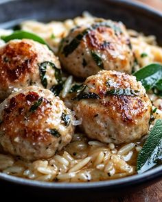 some meatballs and pasta in a bowl on a wooden table with green leafy garnish