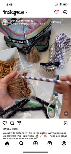 someone holding a straw in their hand over some food on a table with other items