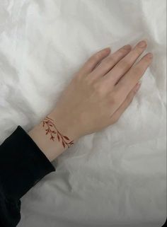 a woman's hand with a small tattoo on her left wrist, resting on a white sheet