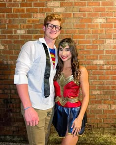 a man and woman dressed up in costumes standing next to each other near a brick wall