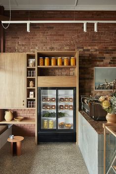 a kitchen with brick walls and shelves filled with donuts on the counter, along with an open refrigerator