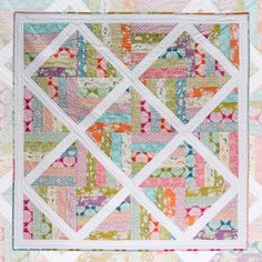 a quilted wall hanging on the side of a pink, green and blue wall