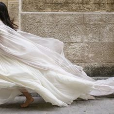 a woman in a white dress is walking down the street with her back to the camera