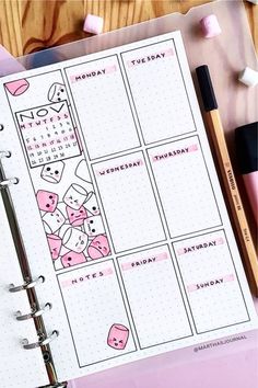 a planner with pink stickers on it next to some pens and pencils,