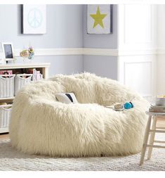 a white bean bag chair sitting on top of a rug in a living room next to a table