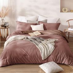 a bed with pink sheets and pillows in a room