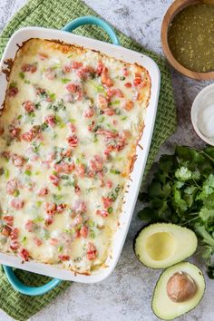 an enchilada casserole with avocado and salsa on the side