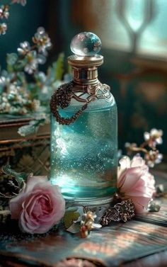 a glass bottle filled with blue liquid next to pink roses and other flowers on a table