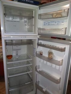 an open refrigerator with its door wide open and the freezer is empty in this kitchen